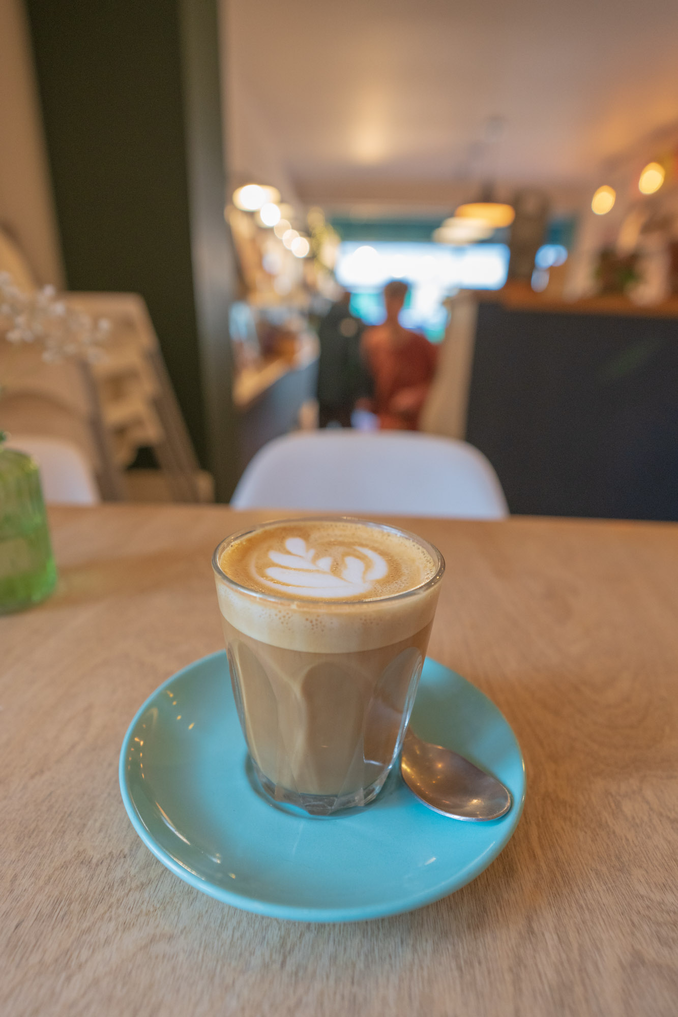 A coffee in a glass on a turquoise saucer